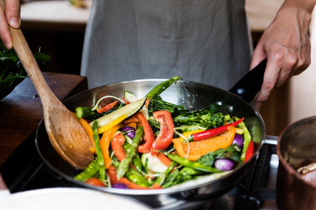 Wholesale vegetables being stir fried in a wok with a professional chef.
