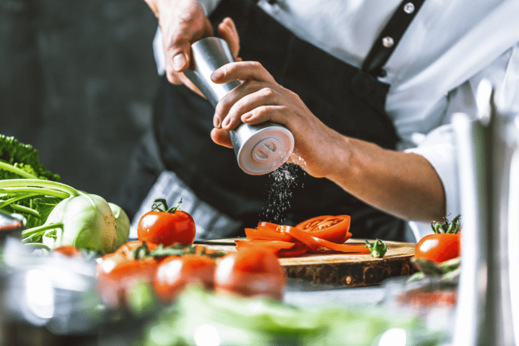 Chef seasoning sliced tomatoes carefully.