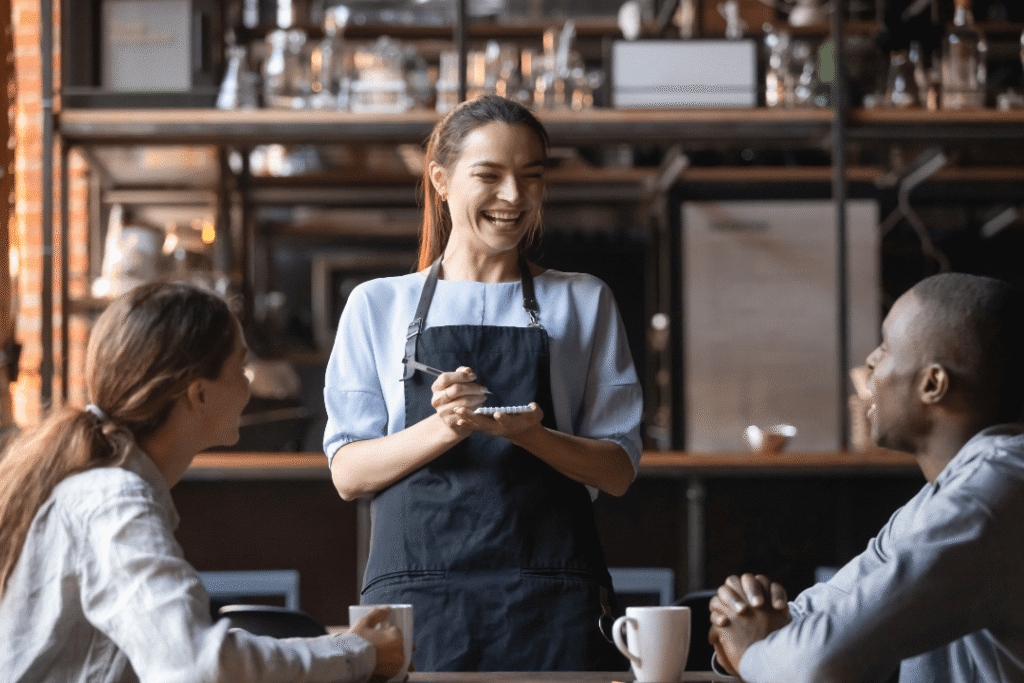 Restaurant waiting staff member interacting with happy customers